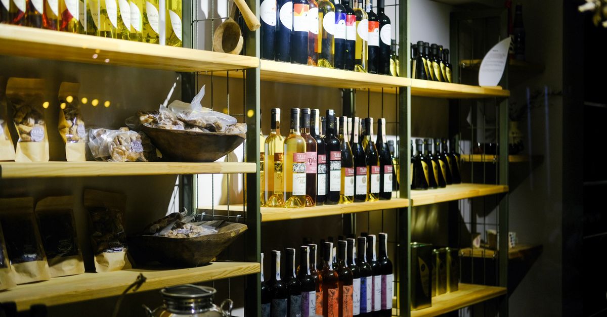 A variety of wine bottles displayed on wooden shelves in a Bozcaada retail store.